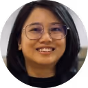 Woman with short black hair and glasses smiling indoors.